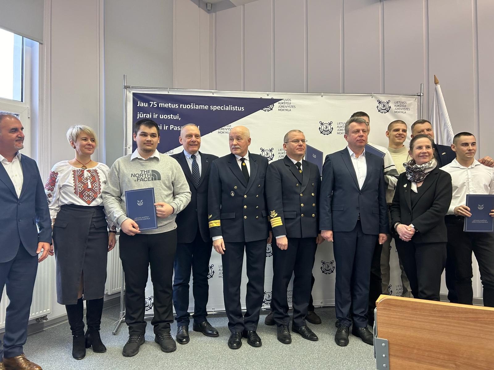 Graduating cadets, academy officials, Head of Trust Katie Higginbottom and MTWTU Chair Oleg Grygoriuk post in front of a Lithuanian Maritime Academy Banner.